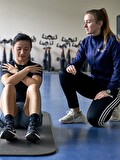 Trainer begeleidt deelnemer met buikspieroefeningen bij SportCentrum Prengerhoekman in Vlagtwedde.